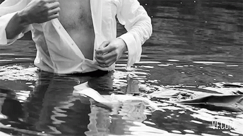 a young man standing in water holding a toothbrush