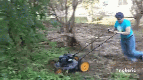 a man pulling a lawn mower in a wooded area