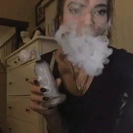 woman smoking weed and looking very angry holding a bottle of booze