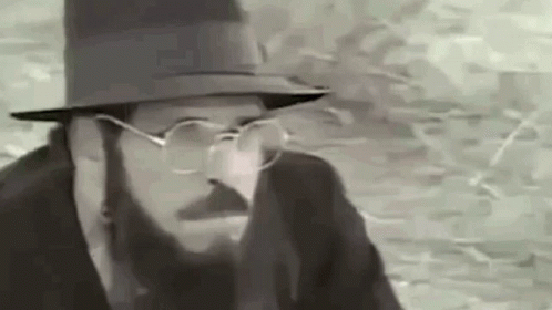 a man in glasses wearing a fedora is seen