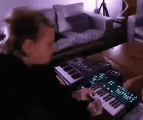 a young man plays a keyboard in his living room