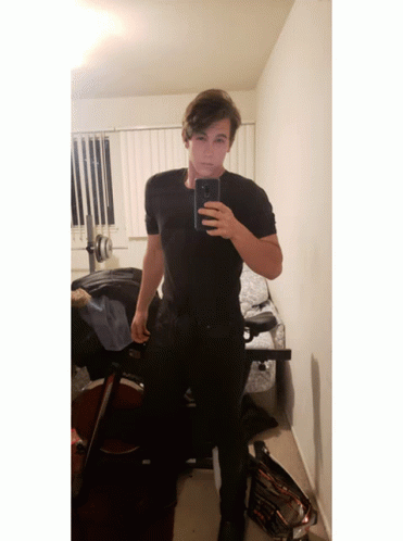 man wearing black pants taking selfie in white bathroom