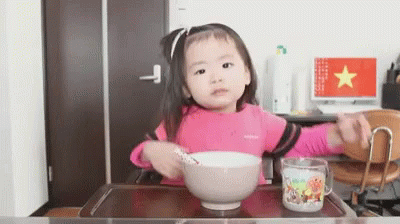 a little girl is making a bowl of cereal