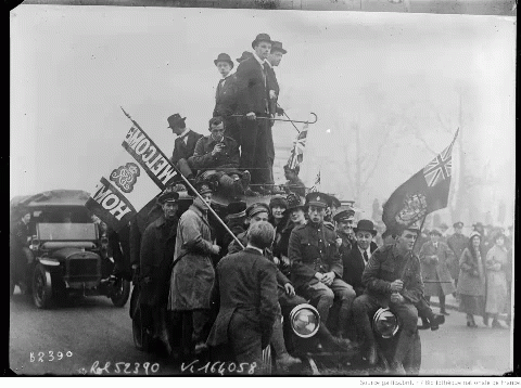 men sitting on top of an antique car with many flags