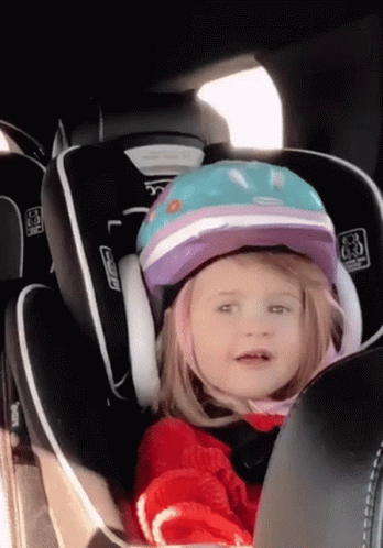 a child is in a car seat with a helmet on