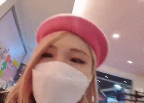 a blue - haired woman wearing a white face mask, in a shopping mall