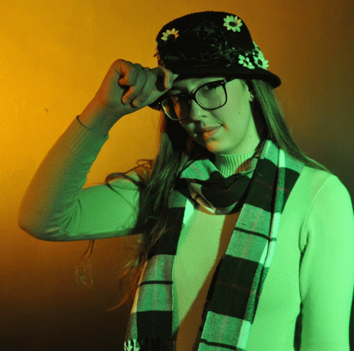 a woman in glasses wearing a plaid scarf and a black hat