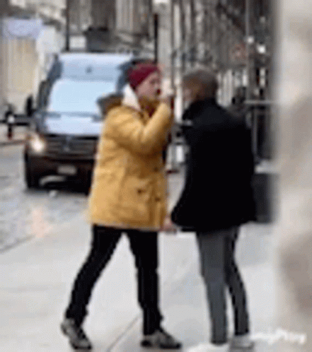 two people on the sidewalk in winter talking to each other
