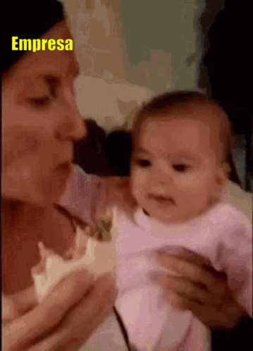 a lady holding a baby while talking on a phone