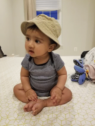 a small baby wearing a hat sitting on a bed
