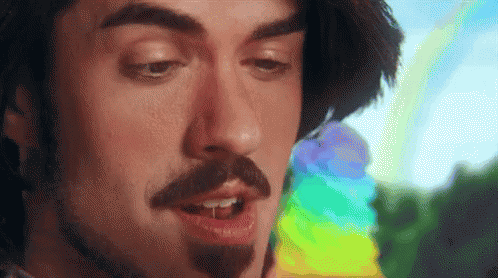 a man with his chin on his chest and a rainbow colored object in the background