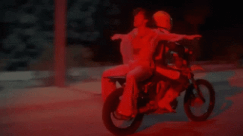 two people riding a small motorcycle on a street