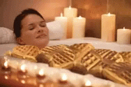 a man laying on a bed next to candles and candles