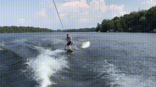a man kiteboarding over a lake while holding onto wires