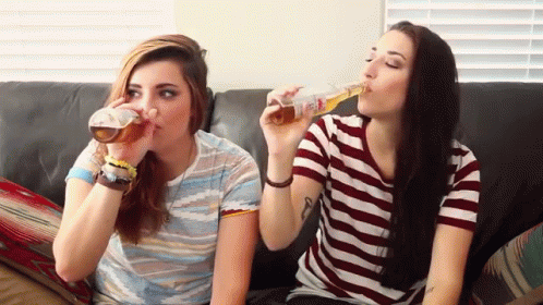 two women on a couch eating donuts and drinking