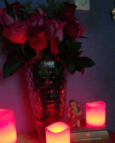 several lit candles sit in front of some flowers