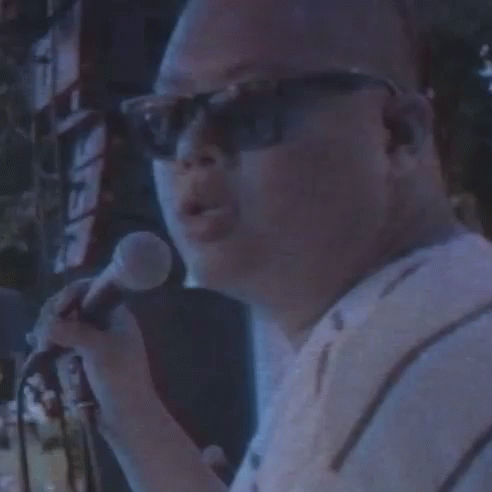 a man speaking into a microphone near a stage