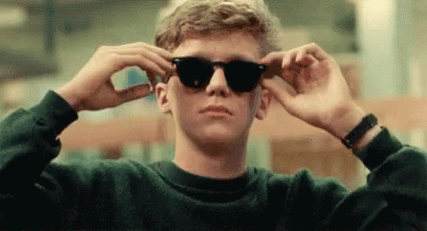 a young man in sunglasses has his hands on his head