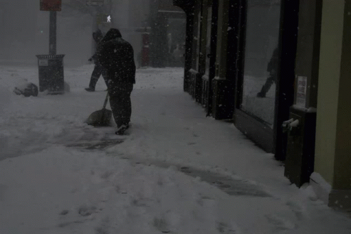 the person is shoveling through the snow from the sidewalk