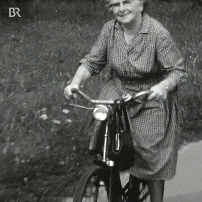 a lady riding a bike down a sidewalk