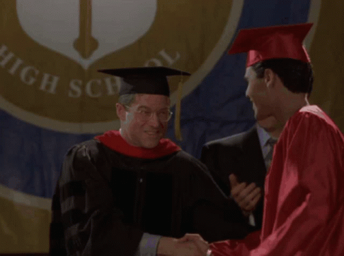 two people in caps and gowns shake hands