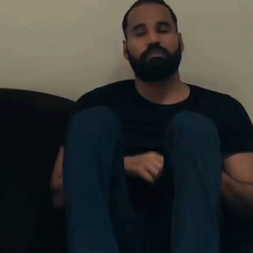 a man with beard sitting on top of a black couch