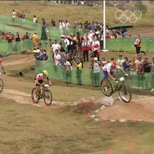 two men compete in a bicyclist race while spectators watch from the stands