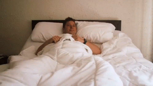 a person in a bed with white blankets