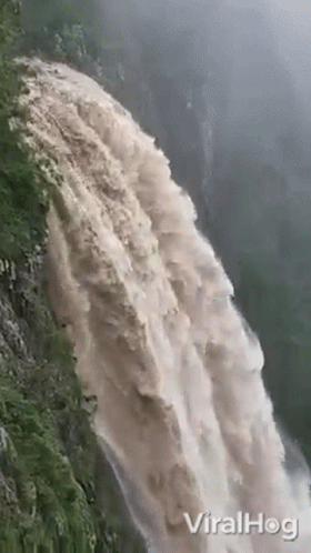 a large water fall spewing from the side of a cliff