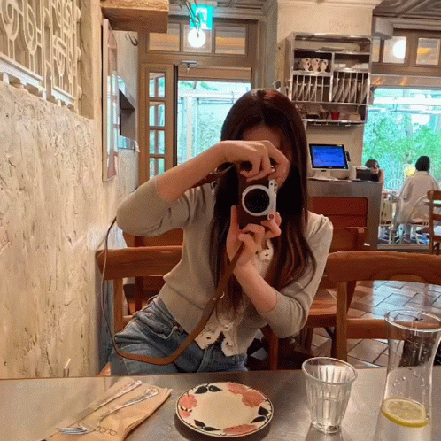 a woman is taking a picture through a glass camera