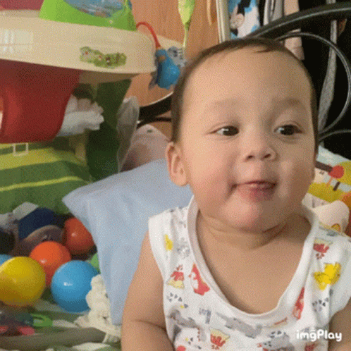 a young baby is smiling in front of some balls