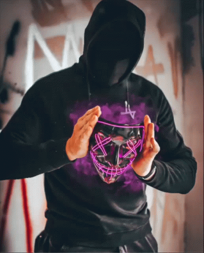 a man in a black hoodie is holding a neon mask