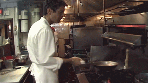 a male in a white coat is working in a kitchen