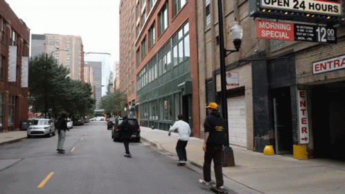 a group of skateboarders ride down a city street
