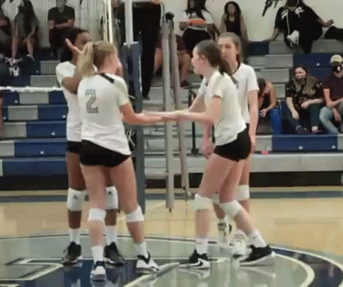 two female volleyball players congratulate each other on a court
