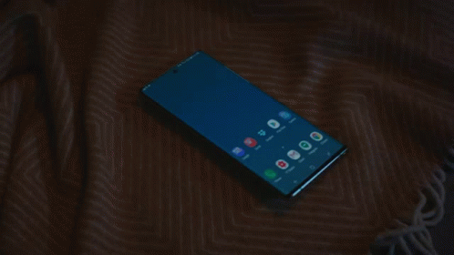 a gold cell phone lying on a blue cloth