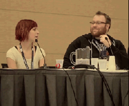 two people are sitting at a table with microphones in front of them