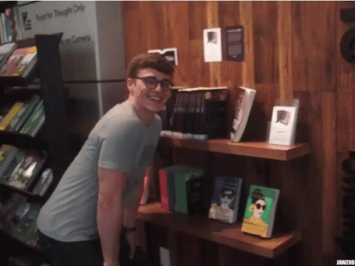 a man standing next to books on a shelf