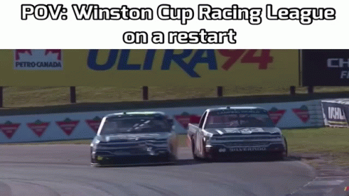 three cars drive down a racetrack in the middle of a race