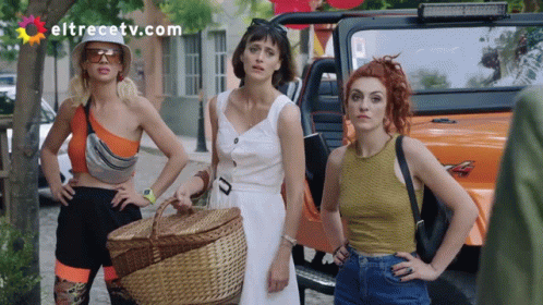 three women pose with their dresses down holding a basket