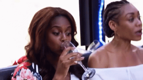 two black women drinking beverages sitting next to each other