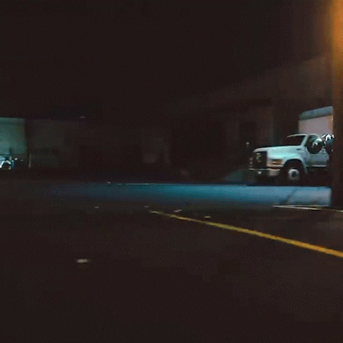 a street at night with two trucks parked in the background