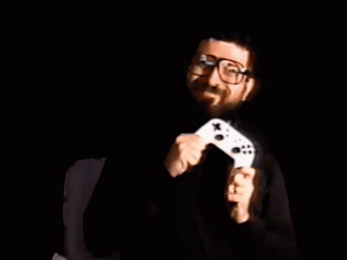 a man in the dark holding a white controller