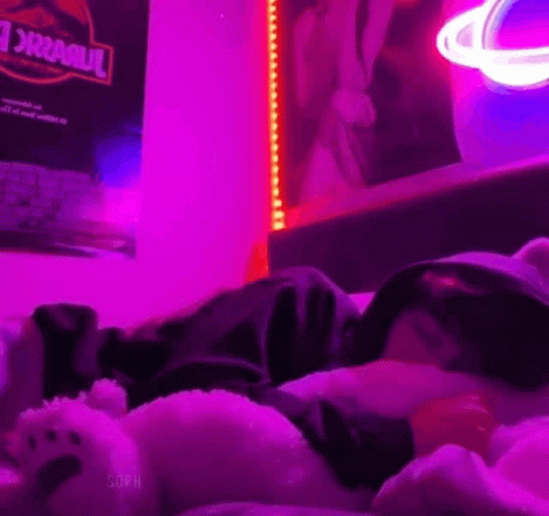 teddy bears sleeping on a bed with a neon light