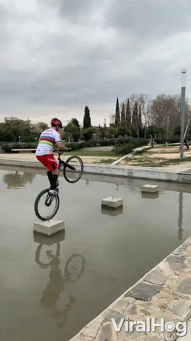 a man jumping up in the air on a bike over a pond