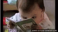 a child looking down at a book while wearing an adult shirt