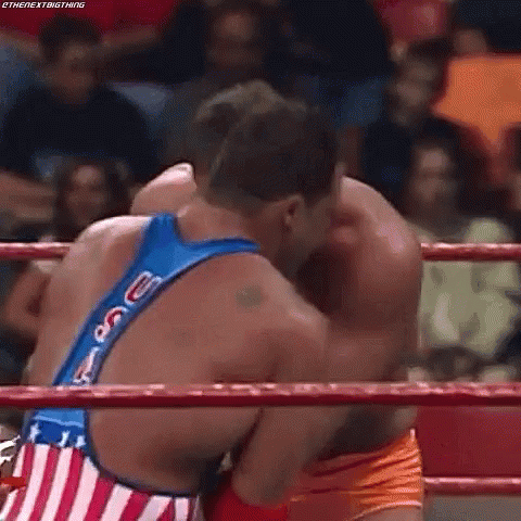 two wrestlers wrestling each other in front of a crowd