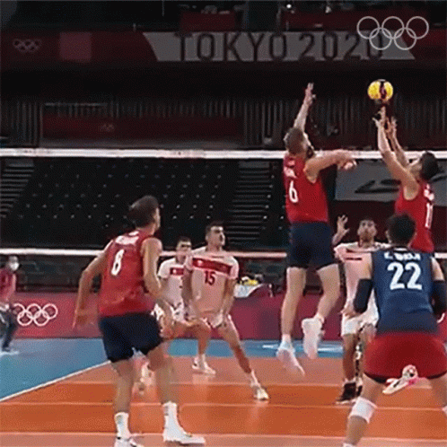 group of men playing volleyball in front of a crowd