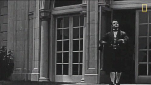 the man is walking in the doorway, in front of the buildings