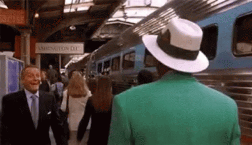 a man wearing a green jacket and hat stands in front of a train